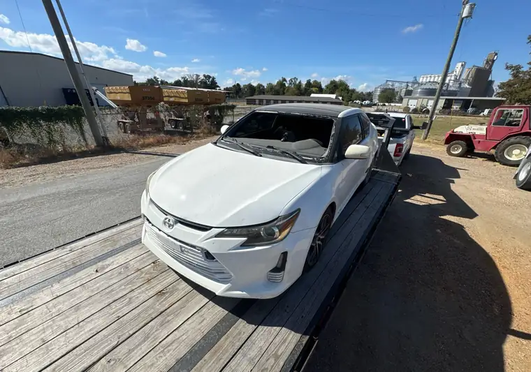White 2014 Scion tC loaded on a flatbed trailer at pickup in Marked Tree, Arkansas