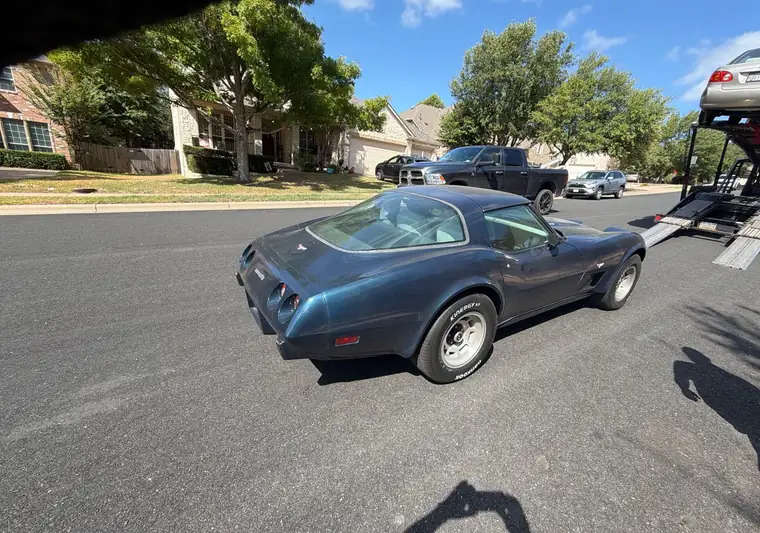 The same 1979 Corvette unloaded from a car carrier on a residential street in Austin, Texas