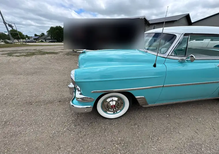 Turquoise and white 1954 Chevrolet Bel Air parked in front of a black enclosed car trailer at pickup in Spirit Lake, Iowa