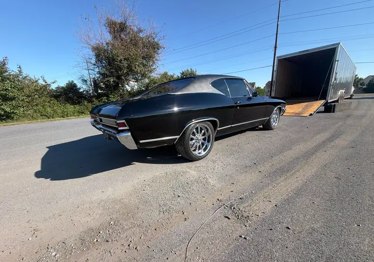 Black 1968 Chevrolet Chevelle beside an enclosed car trailer with its ramp down at pickup in Lewes, Delaware