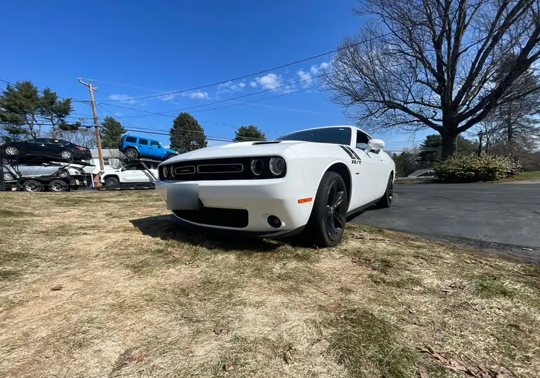White 2018 Dodge Challenger R/T on a lawn at pickup in Southington, Connecticut, with a car carrier behind it
