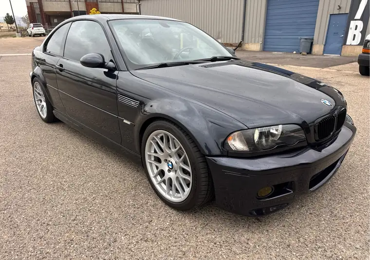 Dark blue 2003 BMW M3 coupe with silver wheels outside a warehouse in Boulder, Colorado