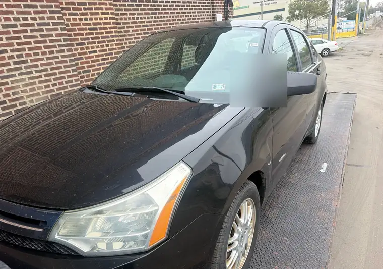 Black 2011 Ford Focus sedan on a car carrier in Philadelphia, Pennsylvania
