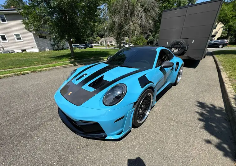 The same Porsche 911 GT3 RS on a residential street at delivery in Paramus, New Jersey, with an enclosed car carrier behind it
