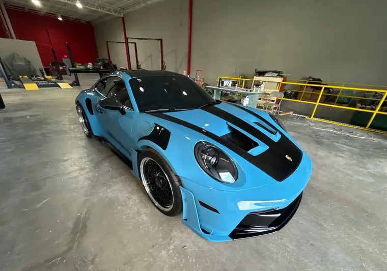 Light blue 2024 Porsche 911 GT3 RS with a carbon fiber hood at pickup in a shop in Doral, Florida