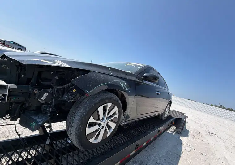 Black 2020 Nissan Altima with front-end damage on a car carrier at a salvage yard in Cahokia Heights, Illinois