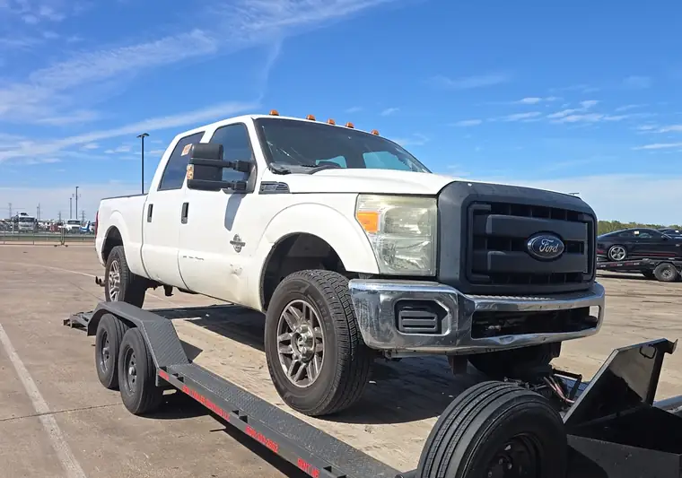 White 2013 Ford F-250 Super Duty crew cab loaded on a trailer at pickup in Hutchins, Texas