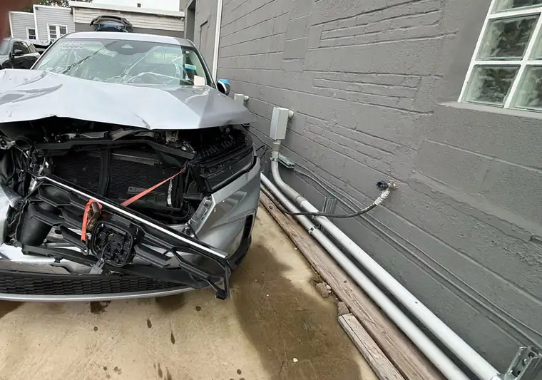 The same Honda Pilot with front-end collision damage beside a building at delivery in Belleville, New Jersey