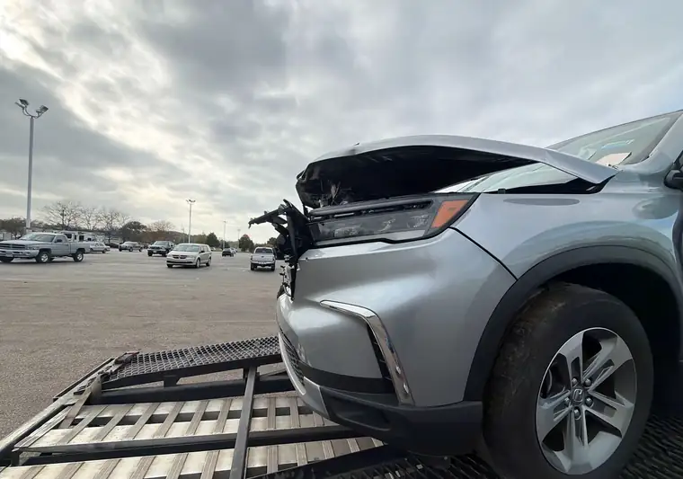 Silver 2023 Honda Pilot with a damaged front end and a raised hood on a car trailer at pickup in Franklin, Ohio