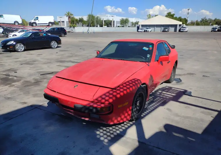 Red 1984 Porsche 944 on a paved auction lot in Chandler, Arizona