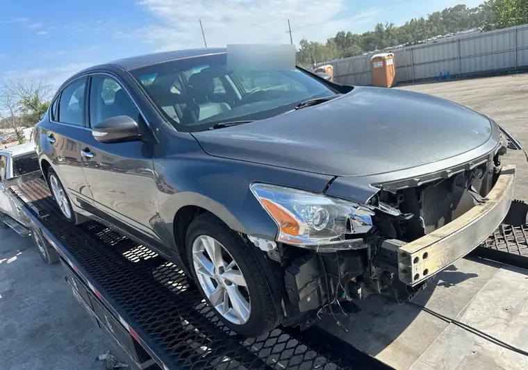 Gray damaged 2015 Nissan Altima on a car carrier at the Copart yard in Kansas City, Kansas