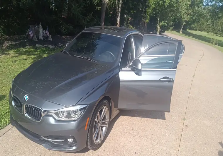 The same BMW 328i with a door open in a driveway at delivery in Venetia, Pennsylvania