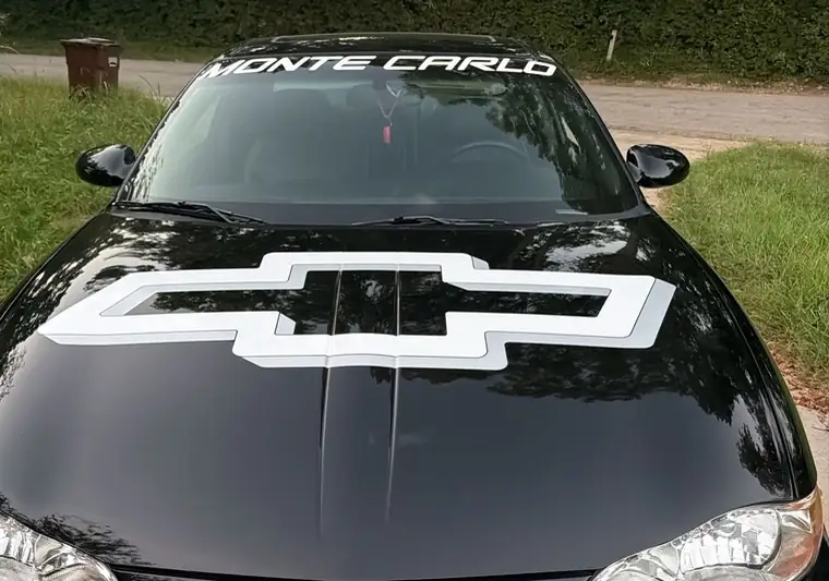 The same Monte Carlo with a white bowtie decal on the hood at delivery in Lexington, Kentucky