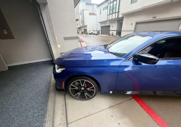 The same BMW M240i beside a garage at delivery in Plano, Texas