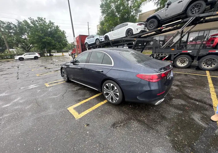 The same Mercedes E350 in a parking lot next to a car carrier at delivery in Metairie, Louisiana
