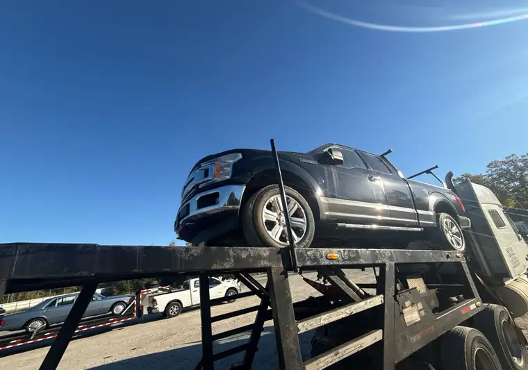 Black 2021 Ford F-150 loaded on an open car carrier at pickup in North Billerica, Massachusetts
