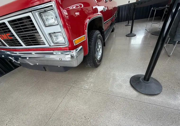 Red 1987 GMC R/V 1500 pickup, front end, inside a showroom in Isanti, Minnesota