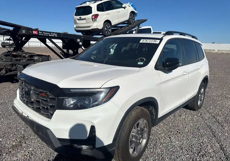 White 2023 Honda Passport on a gravel lot next to a car hauler at pickup in Seymour, Missouri