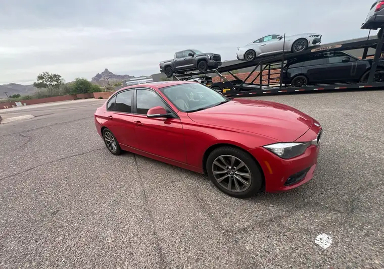 The same BMW 320i in front of an open car carrier at delivery in Fountain Hills, Arizona