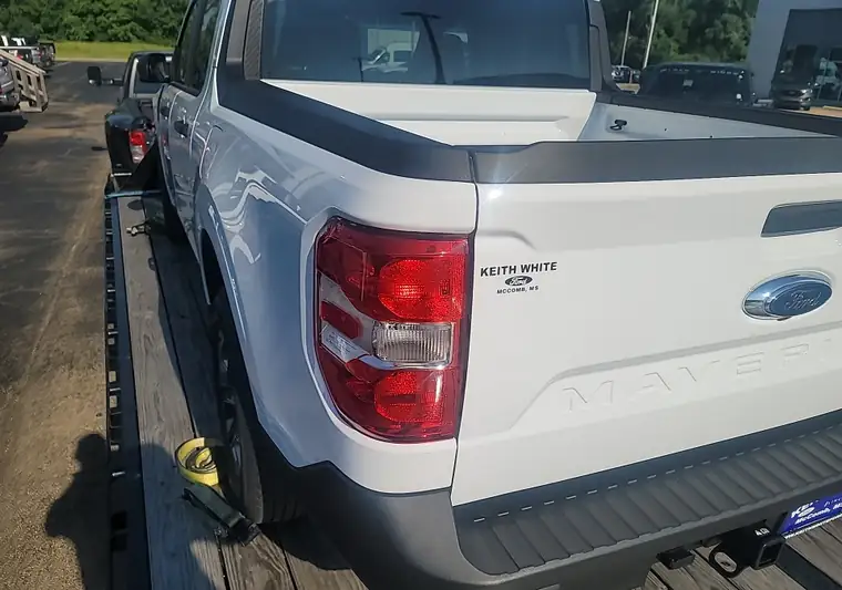 New white Ford Maverick loaded on an open car carrier at pickup in McComb, Mississippi