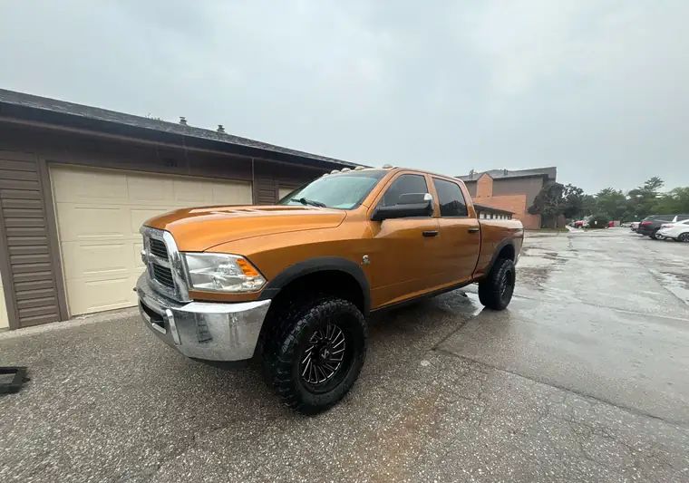 Orange 2012 Ram 3500 on lifted wheels in a parking lot at pickup in Lincoln, Nebraska