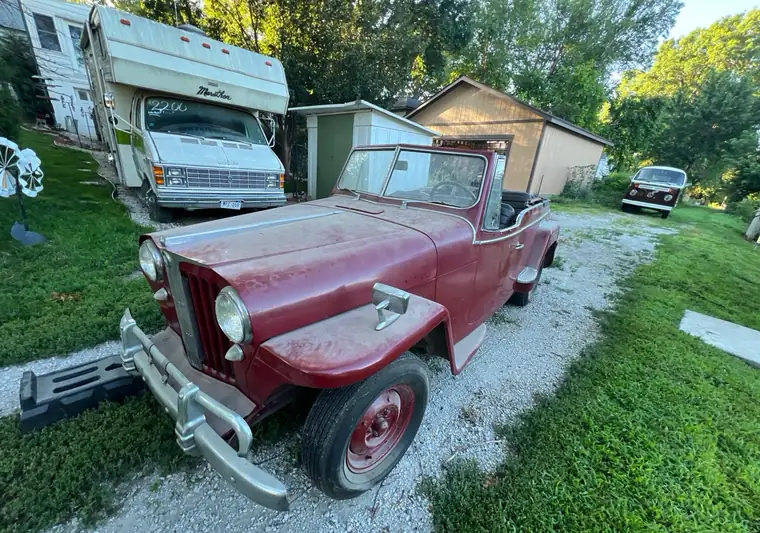 Maroon 1948 Willys Jeepster convertible on a gravel driveway at pickup in Omaha, Nebraska
