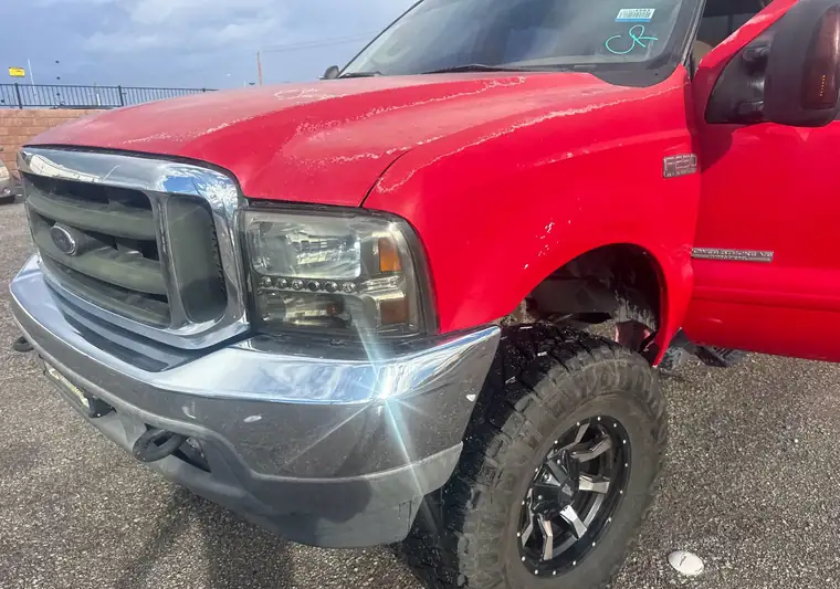 Red lifted 2003 Ford F-250 Super Duty in a parking lot at pickup in North Las Vegas, Nevada