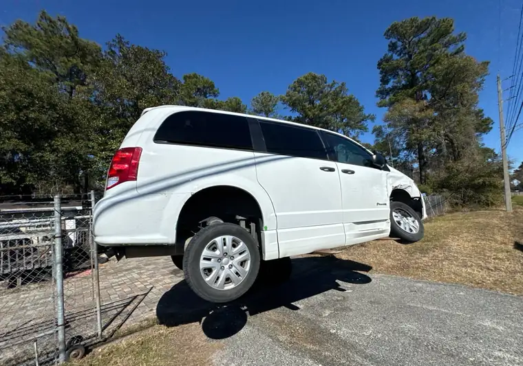 The same damaged Grand Caravan unloaded on a slope at delivery in Jacksonville, Florida