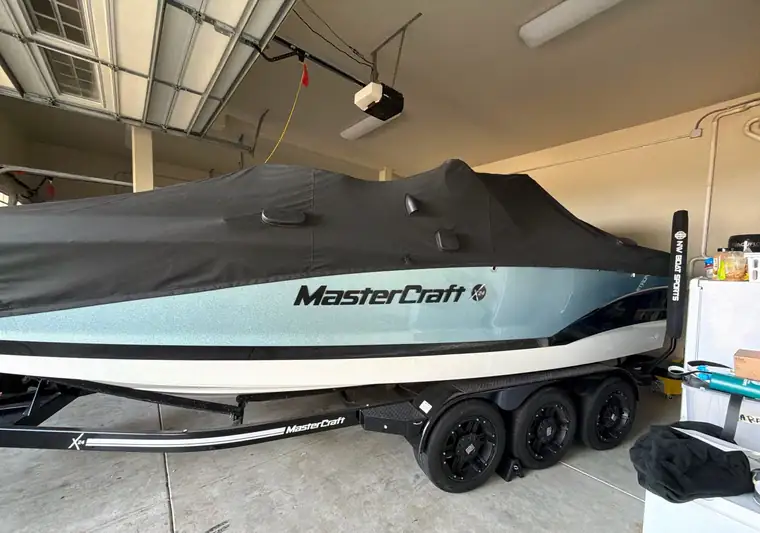 MasterCraft X23 wake boat under a cover on a three-axle trailer in a garage at pickup in Happy Valley, Oregon
