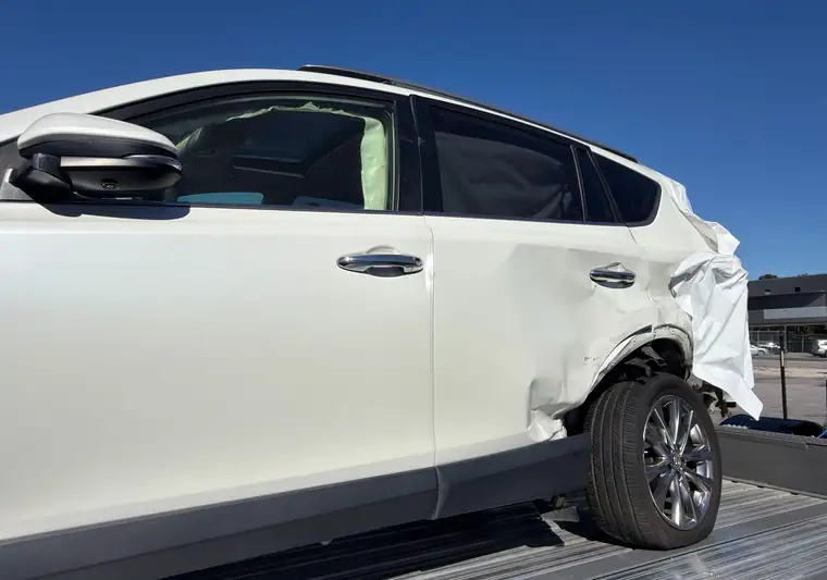 White 2017 Toyota RAV4 with rear-quarter damage on a hauler at pickup in Lexington, South Carolina