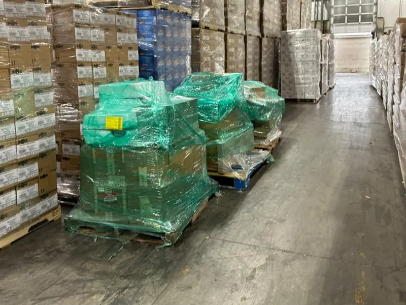 Shrink-wrapped pallets of freight ready for pickup in a warehouse aisle